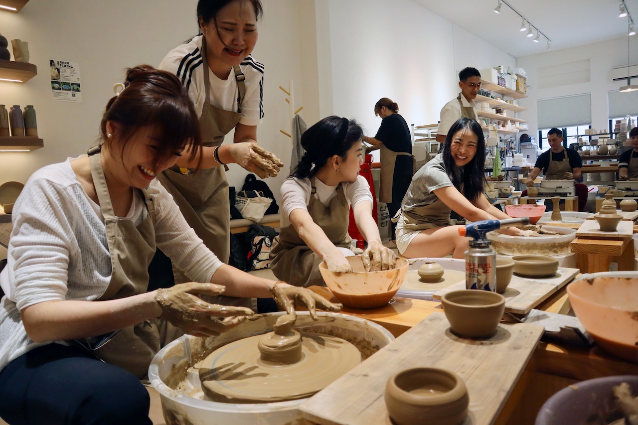 Small-group pottery class focusing on wheel throwing techniques.